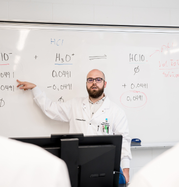 Gabriel Marineau Plante, professeur de chimie, enseigne devant un tableau blanc.